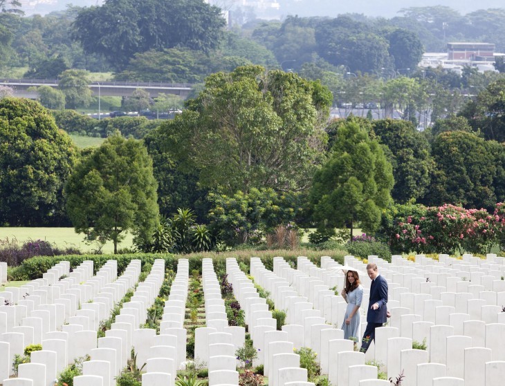 Photo of Kate and William walking through rows of white gravestones at a semi-tropical cemetery