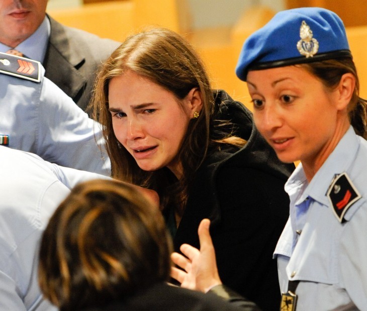 Amanda Knox cries as she is led out of court by a female guard in a beret