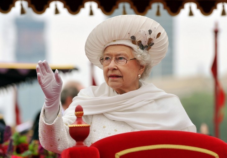 Photo of Queen Elizabeth in a white dress and scarf, waving to crowds