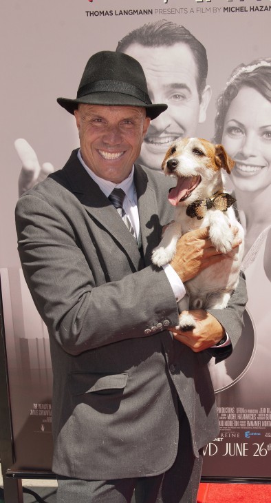 Photo of Uggie the terrier, in a bow tie, being held by his smiling trainer who wears a snappy fedora