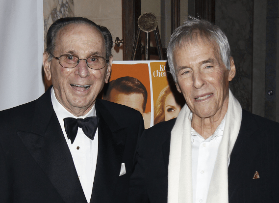 Photo of Hal David, balding and in a tux, with a wan-looking Burt Bacharach in a fancy scarf