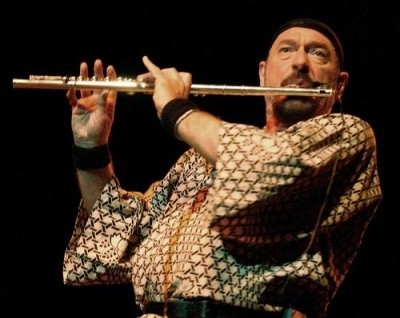Photo of an older Ian Anderson playing the flute in a skull cap