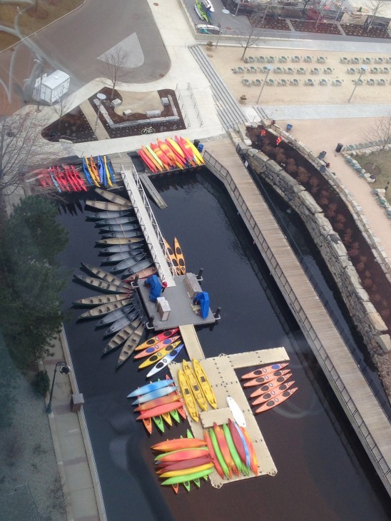 Photo of colorful kayaks laid out on a dock, next to rows of folding chairs
