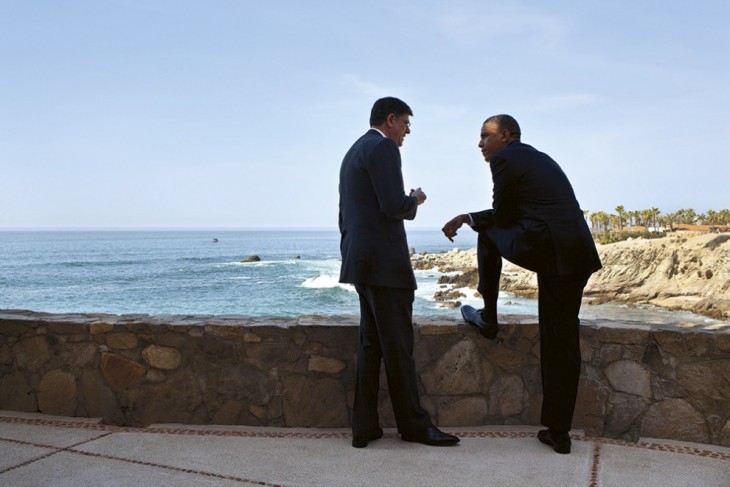 Photo of Jack Lew, standing by a stone wall with the ocean in the background, talking to Barack