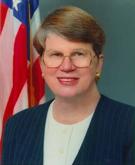 Janet Reno poses in front of a US flag