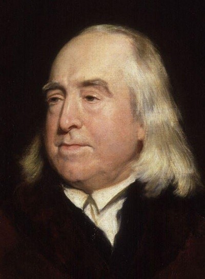 A portrait of Jeremy Bentham, in a black suit with round face and flowing white hair