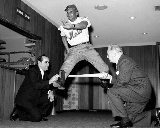 A photo of Jesse Owens in a Mets jersey, leaping over a bat held by two men in suits