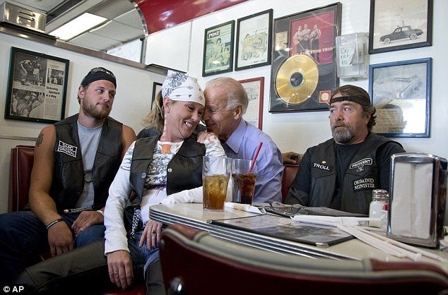 Photo of Joe Biden with a lady biker in his lap, both laughing as he whispers to her