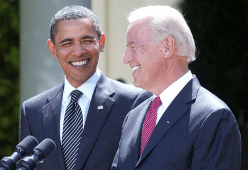 A photo of Joe biden at a Rose Garden podium, smiling with Barack Obama