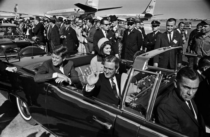 Photo of JFK and John Connally in a long black limo, with the top open