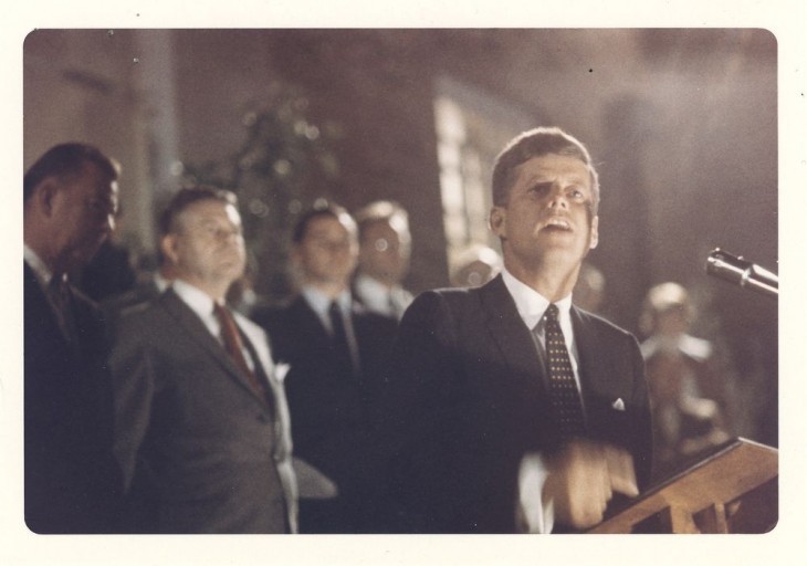 John F. Kennedy photo, showing him chopping air with his hand as he talks at an outdoor podium