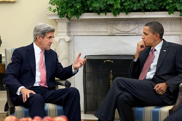 A photo of John Kerry and Barack Obama in armchairs in the Oval Office, talking