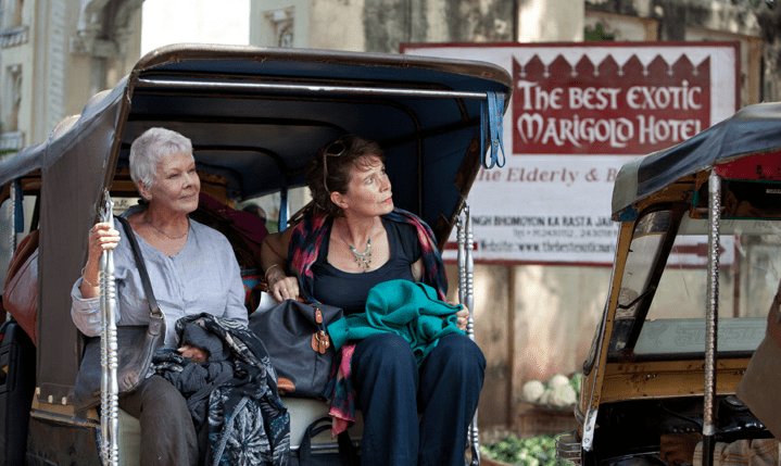 Photo of Judy Dench and less famous co-star riding in a kind of motor rickashaw and smiling at India