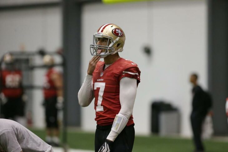 Photo of Colin Kaepernick licking his fingers as he prepares to take a snap at practice