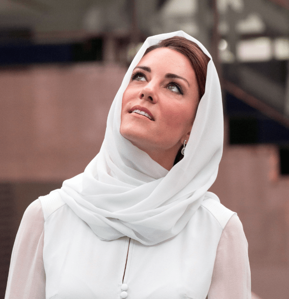 Photo of Kate Middleton in white veil and dress, smiling as she looks up to her left