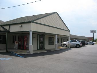 Photo of a classic motel with a long row of rooms and a small modern porch tacked on in front