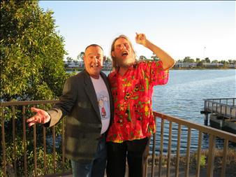 Two 50-something men, Linus with a beard, stand together in front of a river