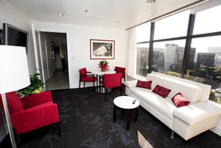 Photo of a luxury living room with white couch, red chairs, and an LA view