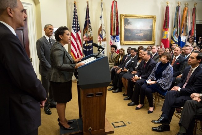 Photo of Loretta Lynch standing at a podium as Barack Obama looks on
