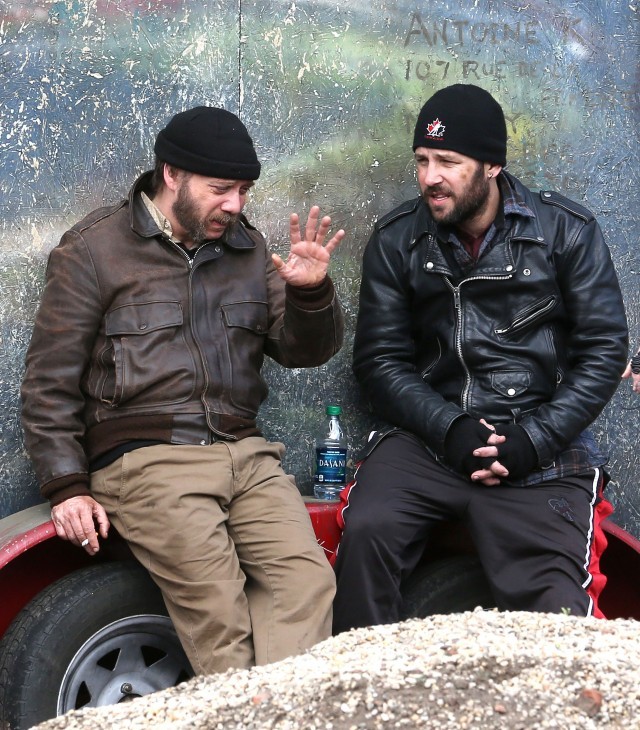 Photo of Paul Giamatti waving his hand as he talks with Paul Rudd, leaning on a trailer bumper