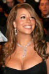 A photo of Mariah Carey in a low-cut black dress, with diamond necklace and a broad smile