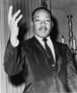 Photo of Martin Luther King, Jr. looking calmly straight at the camera with one hand oratorically upraised