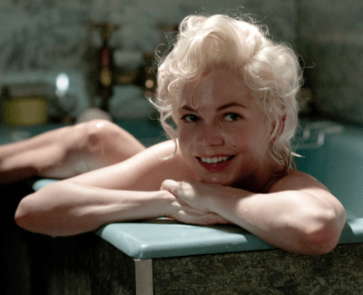 Michelle Williams in a tub, smiling, as Marilyn Monroe