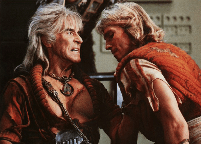 Photo of Ricardo Montalban as Khan, holding a subordinate by the tunic and growing into his face