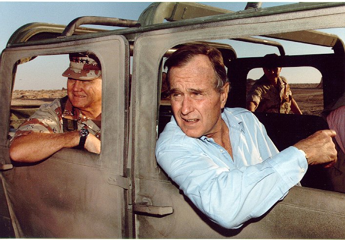 A photo of Gen. Norman Schwarzkopf rides in the back seat of a humvee, as President Bush hangs out the front passenger window