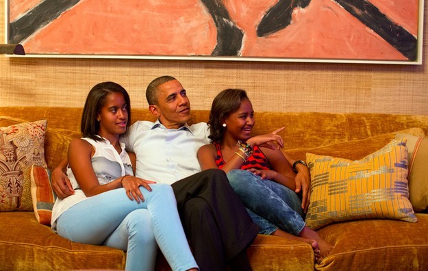 Photo of Barack Obama on a couch with a daughter under each arm