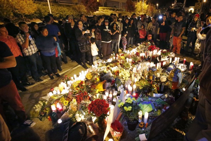 A group of fans crowd around a Paul Walker shrine of flowers and candles at night on a city street