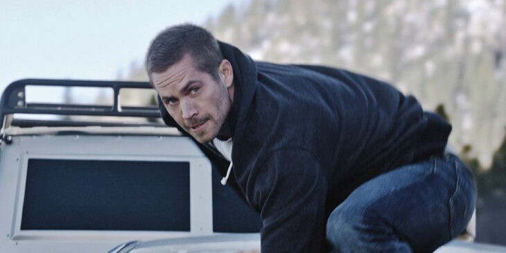 Paul Walker, face grizzled, prepares to leap from a moving car