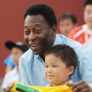 A man holds up a Brazil football jersey in front of a smiling child
