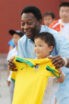 A man holds up a Brazil football jersey in front of a smiling child