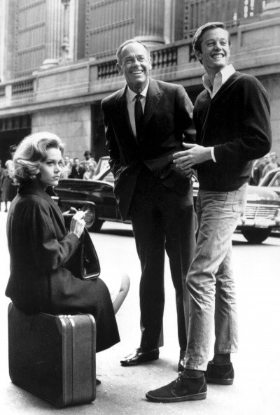 Photo of Jane Fonda sitting on a suitcase, in make-up, while Peter Fonda and Henry Fonda laugh nearby