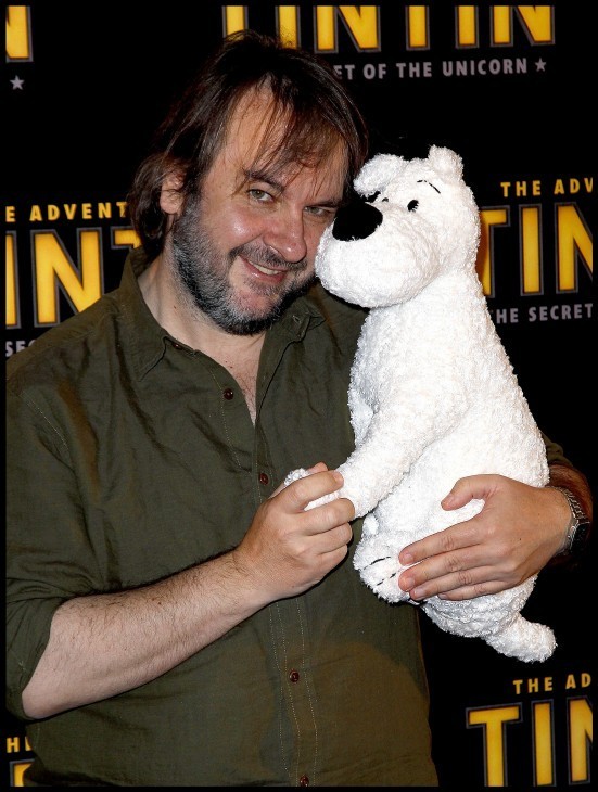 Peter Jackson smiles as he cuddles a stuffed dog with curly white fur