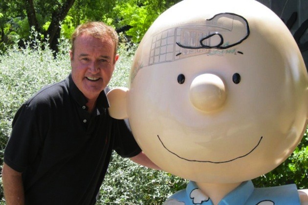 A photo of Peter Robbins next to a huge Charlie Brown statue