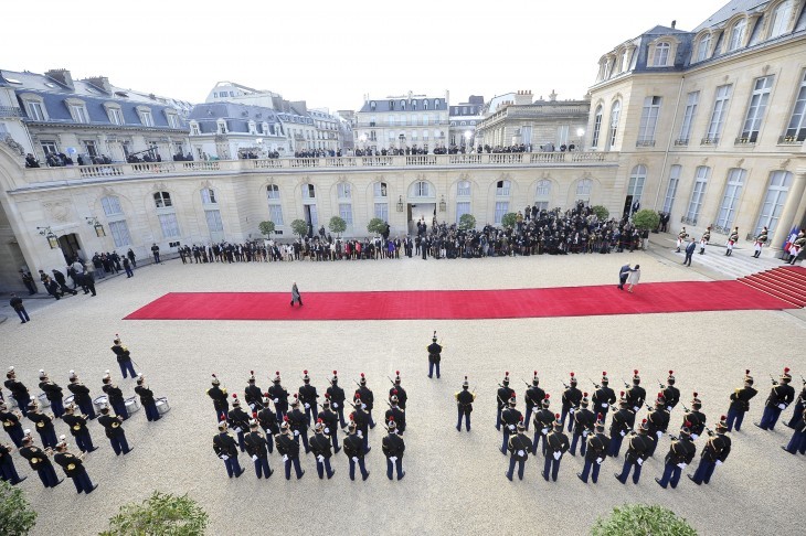 A photo of the courtyard at Elysee Palace, with soldiers lined up by a red carpet