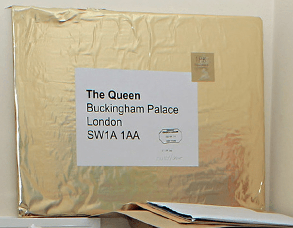 A huge shiny gold envelope is addressed to 'The Queen / Buckingham Palace / London England'