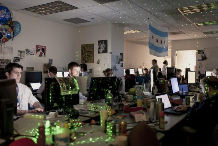 Photo of many men sitting at computers in a darkened room