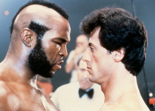 Mister T and Sylvester Stallone try to look tough as they stare at each other in a pre-boxing-match faceoff