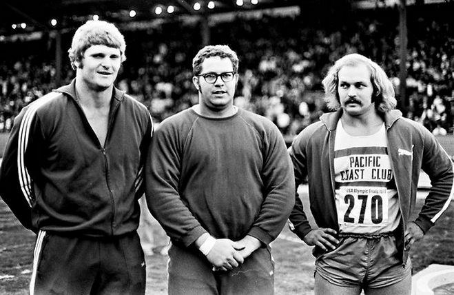 Three burly, even chunky, shotputters in old-fashioned gray sweats and long hair