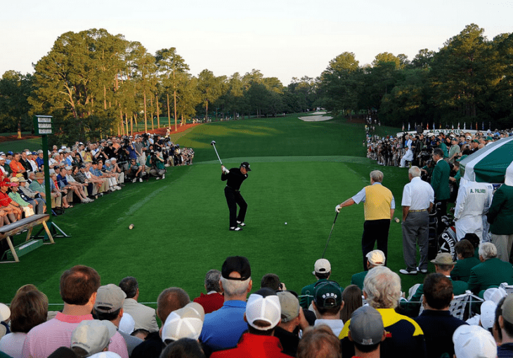 Photo of Gary Player, surrounded by fans, hitting a tee shot on a green, green golf course