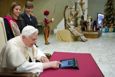 Pope Benedict XVI touches an iPad with his finger in front of smiling young people