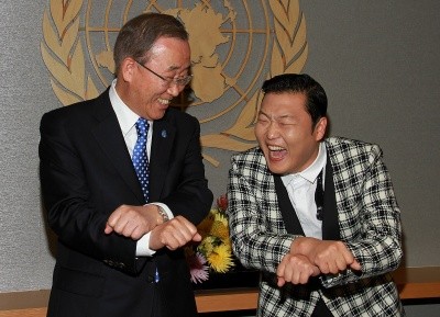 Photo of Ban Ki-Moon and Psy, laughing, as they cross hands for the 'horse dance'