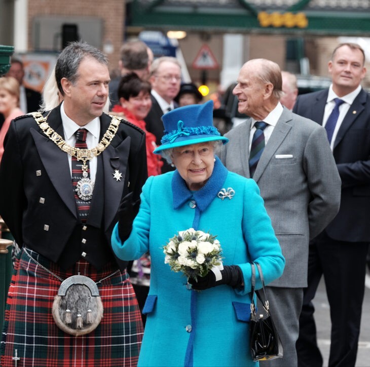 Queen Elizabeth waves to fans in her blue coat