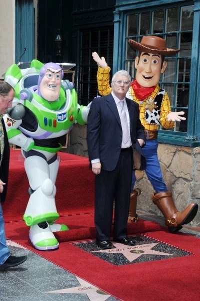 Randy Newman walks on a red carpet with people dressed as 'Toy Story' characters