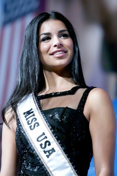 A photo of Rima Fakih in a black dress and a sash reading MISS USA.