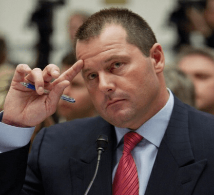 Photo of Roger Clemens touching his brow while looking solemn as he sits before Congress