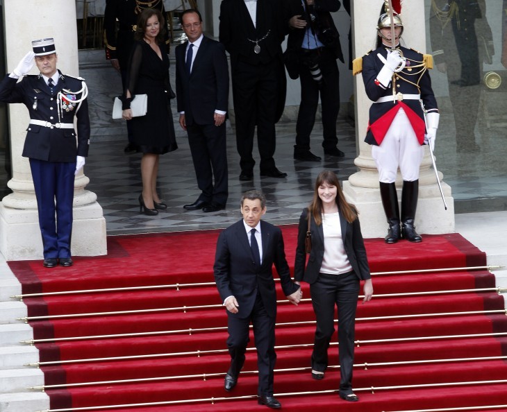 Nicolas Sarkozy and Carla Bruni walk hand-in-hand down red carpeted stairs